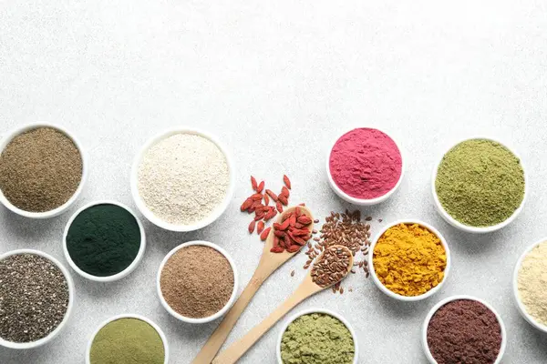 Açık gri masadaki farklı süper yiyecek tozları, düz yatıyordu. Metin için boşluk