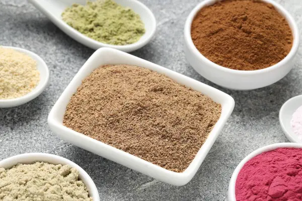 Gri desenli masada farklı süper yiyecek tozları, yakın plan.