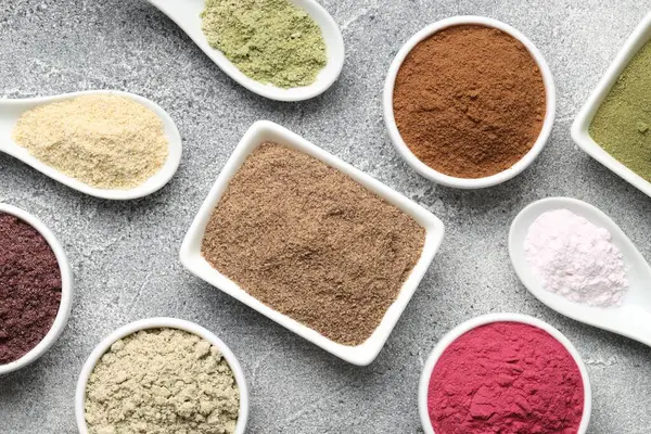 Gri desenli masa üzerinde farklı süper yiyecek tozları, düz uzanmış.