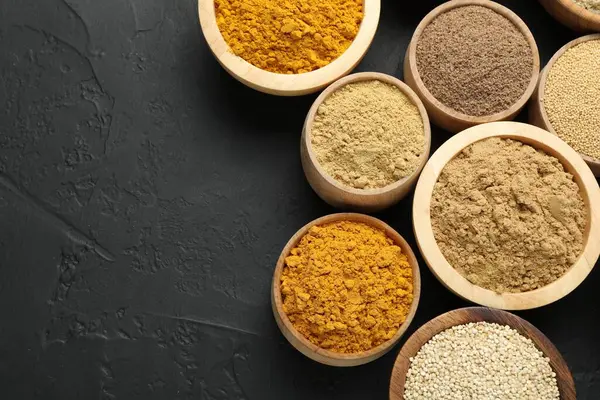 Koyu dokulu masada, düz yerde, kaselerde farklı süper yiyecek tozları var. Metin için boşluk