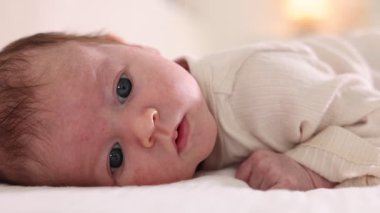 Sevimli yeni doğmuş bebek yatakta uzanıyor, yakın plan.