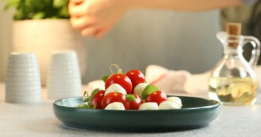 Kadın mozzarella peyniri, domates ve fesleğenle aperatif hazırlıyor.