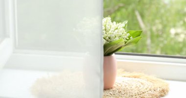 Pencere kenarındaki vazoda bir buket nilüfer çiçeği var.