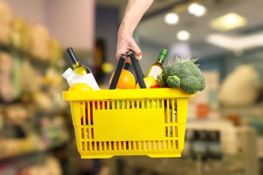 Süpermarkette elinde farklı gıda ürünleri olan bir adam var.