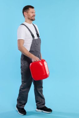 Açık mavi arka planda plastik kutu tutan adam.