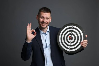 Hedef alınıyor. Ok ve dart tahtası olan adam gri arka planda iyi bir hareket gösteriyor.