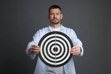 Hedef alınıyor. Gri arka planda dart tahtası olan adam.