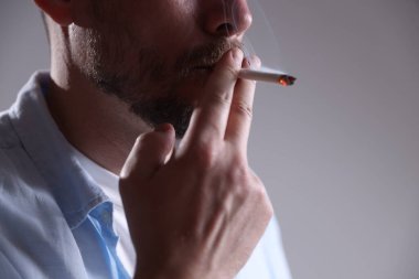 Arka planda sigara içen adam, yakın plan.