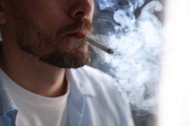 Arka planda sigara içen adam, yakın plan.