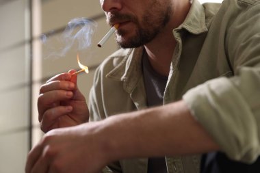 Arka planda kibrit yakan adam, yakın plan.