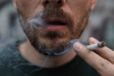 Arka planda sigara içen adam, yakın plan.