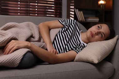 Bunalımlı kadın evdeki kanepede yatıyor.