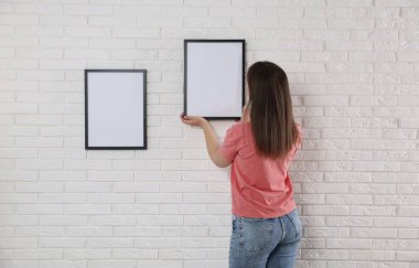 Beyaz tuğla duvara boş çerçeveler asan kadın, arka plan