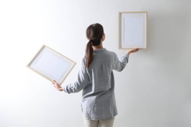 Beyaz duvara boş çerçeveler asan kadın, arka plan