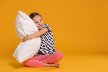 Turuncu arka planda yastığı olan tatlı bir kız. Metin için boşluk