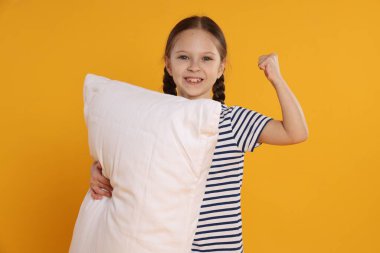 Turuncu arka planda yastığı olan tatlı bir kız.