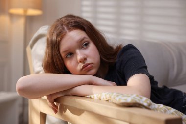 Evdeki kanepede oturan üzgün genç kız.