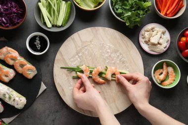 Koyu gri masada nefis börek yapan bir kadın.