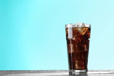 Kola, koyu desenli masa üzerindeki buzlu buzlarla turkuaz gradyan arka planda tazeleniyor. Yakın plan. Metin için boşluk