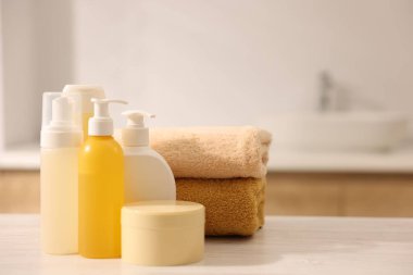 Banyodaki beyaz ahşap masada farklı banyo ürünleri.