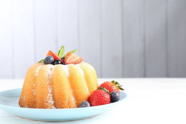 Beyaz ahşap masada pudra şekeri ve böğürtlenli Lezzetli kek, yakın plan. Metin için boşluk