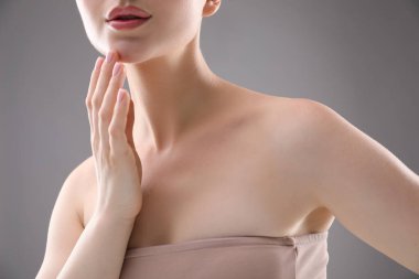 Gri arka planda güzel köprücük kemikleri ve boynu olan kadın, yakın plan.