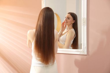 Güzel bir kadın aynada kendine bakıyor.