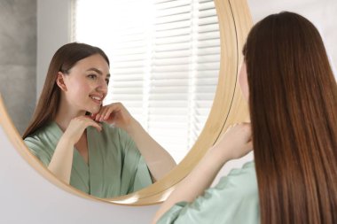 Güzel bir kadın aynada kendine bakıyor.