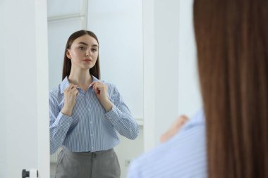 Güzel bir kadın aynada kendine bakıyor.