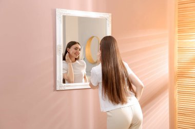 Güzel bir kadın aynada kendine bakıyor.