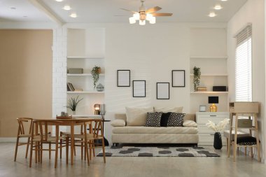 Rahat bir kanepe, masa, sandalyeler ve içeride şifonyer. İç tasarım