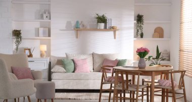 Odada rahat bir kanepe ve sandalyeli şık bir yemek masası. İç tasarım