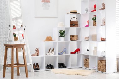 Ayakkabı deposu. Farklı ayakkabı, aksesuar, tabure ve aynaya sahip raf ünitesi.