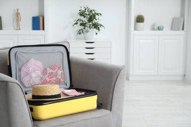 İçinde farklı kıyafetler, şapka ve pasaport bulunan bavulu açık tut. Metin için boşluk