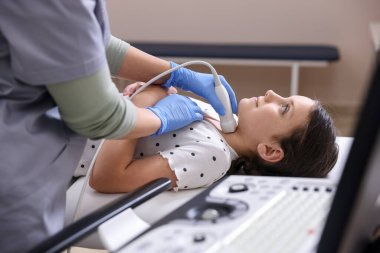 Sonograf, klinikte kızın tiroid bezi ultrason muayenesini yönetiyor.