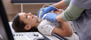 Sonograf, klinikte kızın tiroid bezi ultrason muayenesini yönetiyor.