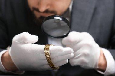 Masadaki lüks kol saatini değerlendiren eksper, yakın plan.