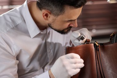 Kapalı alanda deri çanta değerlendirmesi yapan bir eksper.