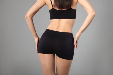 Gri arka planda mükemmel ince vücutlu kadın, yakın plan.