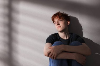 Gençlik sorunları. Gri duvarın yanında depresyondaki genç çocuk, mesaj için yer var.