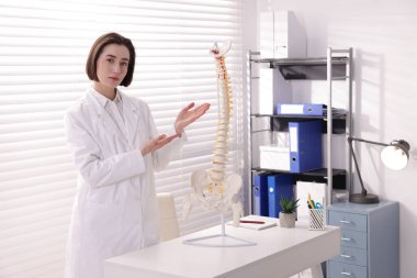 Doktor, klinikteki masada insan omurgası modelini gösteriyor.