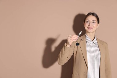 Emlakçının elinde anahtar bej arka planda ev şekilli anahtarlık, metin için boşluk var.