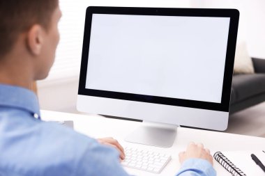 Ofisteki beyaz masada bilgisayarda çalışan bir adam, yakın plan. Tasarım için model