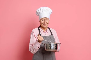 Profesyonel şekerci pembe arka planda krema yapıyor.