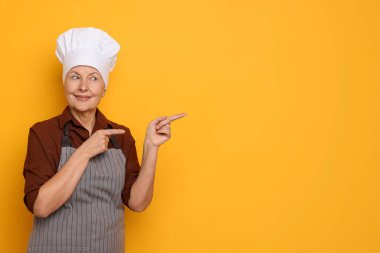 Turuncu arka plandaki bir şeyi işaret eden profesyonel bir şekerci. Metin için boşluk