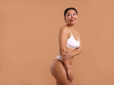 Beyaz iç çamaşırlı, pürüzsüz ciltli bir kadın bej arka planda epilasyon işleminden sonra, metin için boşluk