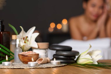 Güzel bir kadın masaj koltuğunda dinleniyor, farklı spa ürünlerine ve zambak çiçeklerine odaklanıyor.