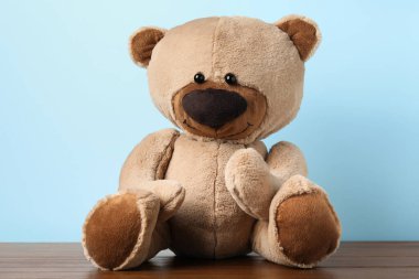 Ahşap masada açık mavi arka planda sevimli bir oyuncak ayı.