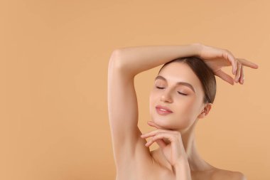 Bej arkaplandaki epilasyondan sonra pürüzsüz cilt gösteren genç kadın, metin için boşluk