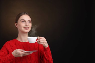 Kahverengi arka planda bir fincan kahveyle gülümseyen kadın. Metin için boşluk